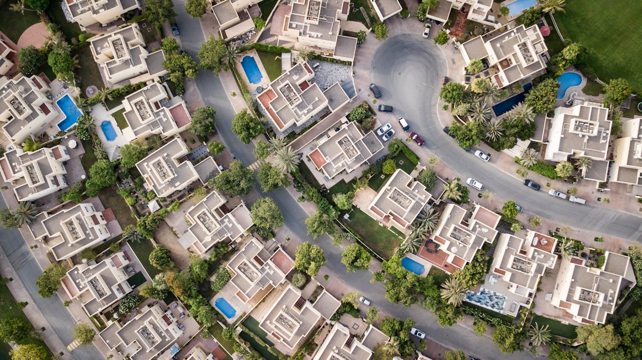 hero-homepage Explore a stunning aerial view of a residential area in Dubai with lush greenery and swimming pools.